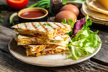 Traditional Mexican tortillas with quesadilla with scramble eggs, vegetables, ham and cheese. Mexican cuisine, Mexico and Latin America traditional restaurant menu dish