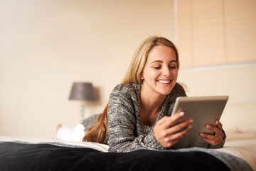 Connecting from the comfort of her bed. Cropped shot of an attractive young woman using a digital tablet at home.