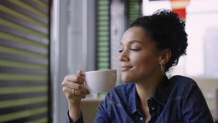 Young happy African American woman enjoying aromatic coffee sitting at the tables in the cafe of the mall. A woman is resting after a successful purchase in fashion clothing store. Close. Slow motion.