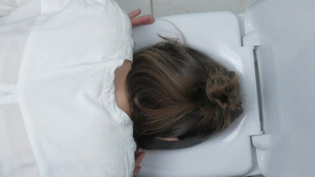 Pregnant woman vomits into the toilet