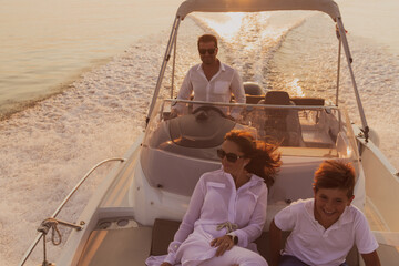 A senior couple in casual outfits with their son enjoy while riding a boat at sea at sunset. The...