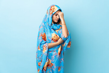 Young Moroccan woman with traditional costume isolated on blue background with headache