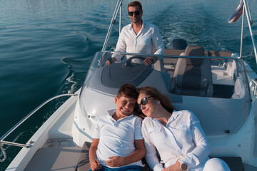 A senior couple in casual outfits with their son enjoy while riding a boat at sea at sunset. The concept of a happy family. Selective focus 