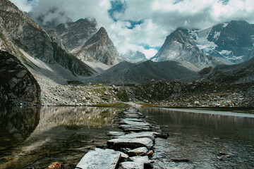 Path formed by a succession of stones crossing the lac patinoire (high altitude lake) in Pralognan in the French Alps