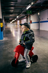 A child on a tricycle playing traffic in an underground garage.