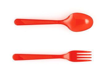 Disposable red plastic fork and spoon on a white background. View from above. Close-up.