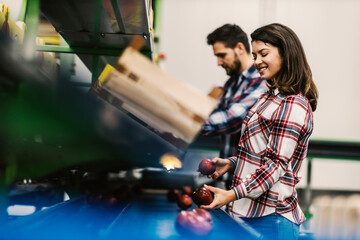 Food factory employees selecting good apples from bad on conveyor belt.
