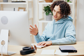 guy with curly hair sitting at a table in front of a computer freelance interior