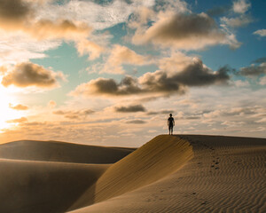 Fototapeta na wymiar Silhueta caminhando na areia em dunas no por do sol em Tutoia, Maranhão 