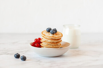Stack of pancakes decorated with blueberry and red currants