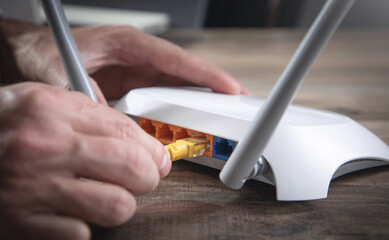 Man plugging internet cable into wifi router.