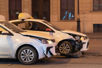 Two cars on the city road after collision. Damaged white automobile on the street after the accident with damaged bumpers, side view. 
