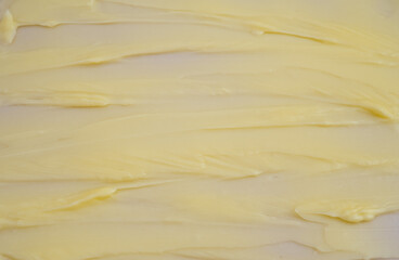 Cosmetic products creamy yellow stain texture on pink background. Texture of natural cosmetics, hair mask, cream, scrub
