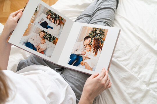 top view woman holds photobook in hands while sitting in bed.family photo shoot 