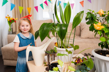 a cute little girl prune the branches of a houseplant 