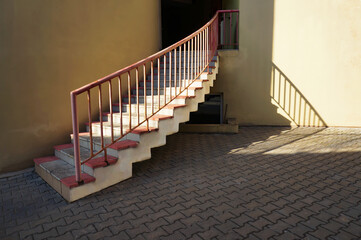 Stairs to entrance into building and railing shadows on wall.