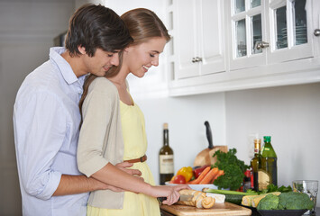 Making dinner lovingly. Shot of a young couple in their kitchen preparing dinner together.