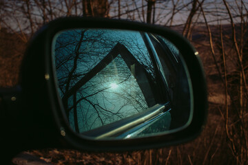 Car mirror through the window on a nice spring day. Trees and sky reflected. Safety driving concept