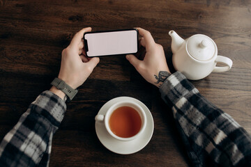 blank white screen mobile phone layout. Male hand holding cellphone on desk in office. Empty background space for advertising. work of people connected with marketing business, technologies