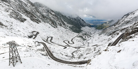 Winding road transfagarasan, mountain valley and the tops of the mountains covered with snow. Panorama of a winter landscape of a mountainous area in cloudy weather. Location Carpathians of Romania.
