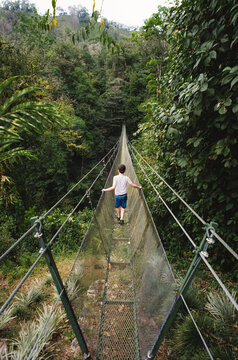 Child crossing hanging suspension bridge in the jungle of Costa Rica.
