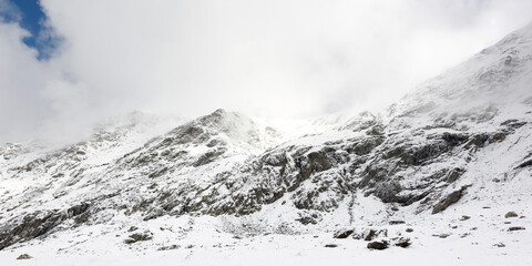 Panorama of a winter landscape of a mountainous area in foggy weather. Snow-covered valley and mountain peaks covered with snow. Location Carpathians of Romania, Transylvania.