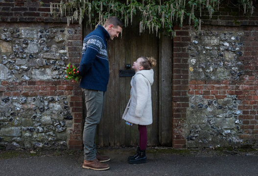father holding flowers behind his back for daughter