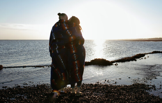 lesbian couple at the beach wrapped in native American blanket