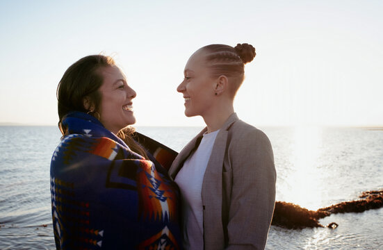 lesbian couple laughing together at the beach at sunset