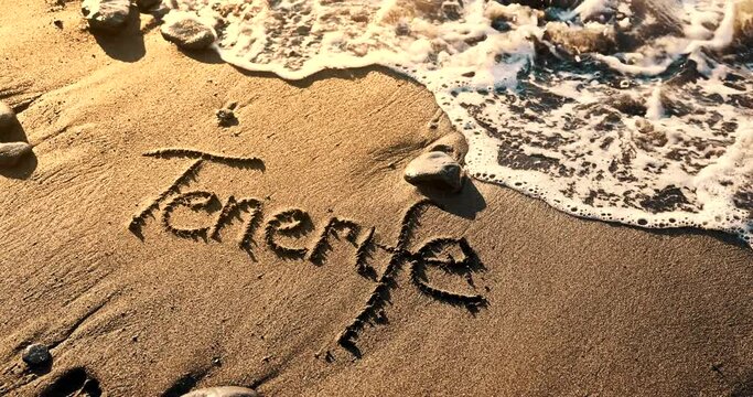 Tenerife text and ocean wave on volcanic beach black sand. slow motion