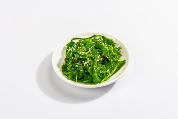Chuka Seaweed Salad with sesame seeds isolated on white background. Trendy hard light, dark shadow