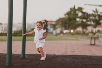 A little girl in modern summer clothes playing in the park in summer. Selective focus 