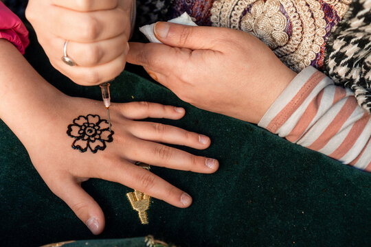 Drawing of henna menhdi tattoo on girl's hands in a medieval market. High quality photo HORIZONTAL