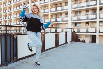 90s adolescence concept. Full outdoor shot of dancing blonde-haired woman in her 20s in baggy jeans...