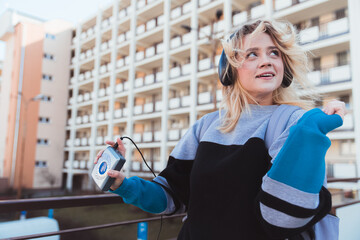 Cool 90s-inspired hipster dancing outdoors and listening to favorite album on tape player. 90s hype...