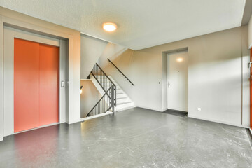 Spacious, bright entrance in a modern house with a stairwell and an elevator with orange doors.