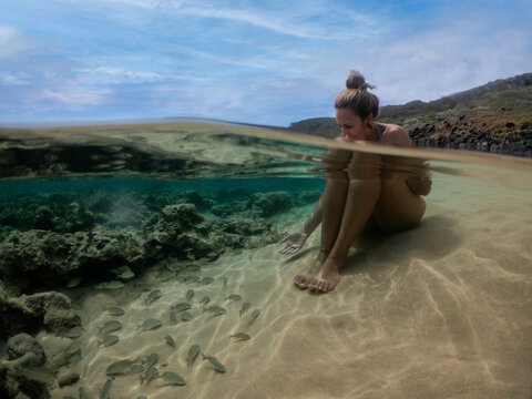 Blonde girl relaxing on water with fishes and marine life. Clear water at Lion Beach, Fernando de Noronha, Brazil