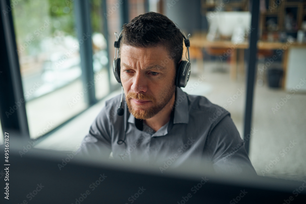 Poster Working hard to resolve all issues for his customers. Shot of a mature man working on a computer in a call centre.