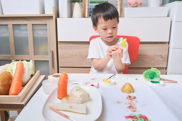 Homeschooling, Cute Asian kindergarten boy child making artwork from vegetable stamping at home,...
