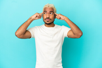 Young Colombian handsome man isolated on blue background having doubts and thinking