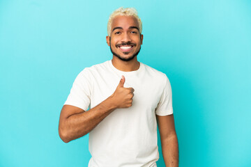 Young Colombian handsome man isolated on blue background giving a thumbs up gesture