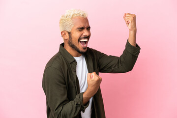 Young Colombian handsome man isolated on pink background celebrating a victory