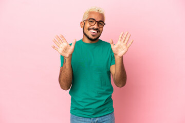 Young Colombian handsome man isolated on pink background counting ten with fingers