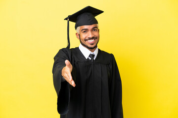 Young university graduate Colombian man isolated on yellow background shaking hands for closing a...