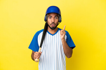 Young Colombian latin man playing baseball isolated on yellow background intending to realizes the solution while lifting a finger up