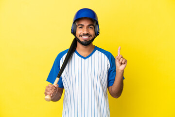 Young Colombian latin man playing baseball isolated on yellow background showing and lifting a finger in sign of the best
