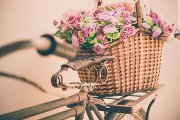 Artificial rose flower in basket on vintage bicycle. Vintage retro color tone.