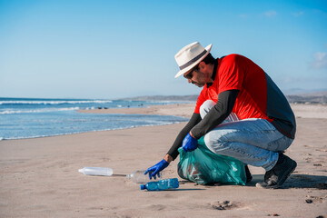 volunteer collects plastic waste on the beach.