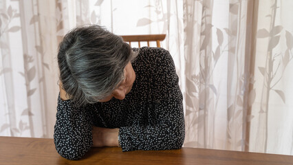 頭をもたげ考え込んでいる黒い服を着た高齢者女性