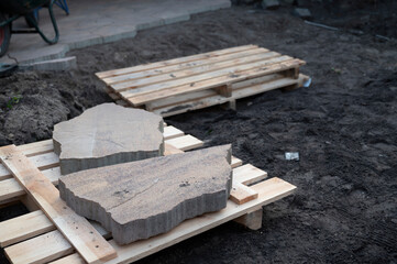 Fototapeta na wymiar Work on laying irregularly shaped concrete tiles in the garden during renovation